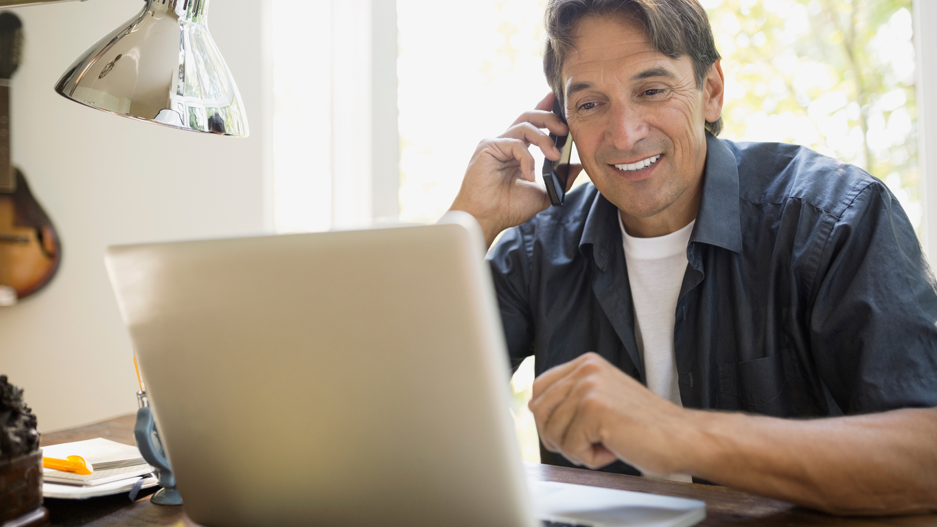 Contact John Deere Financial Man using a phone and looking at a laptop computer