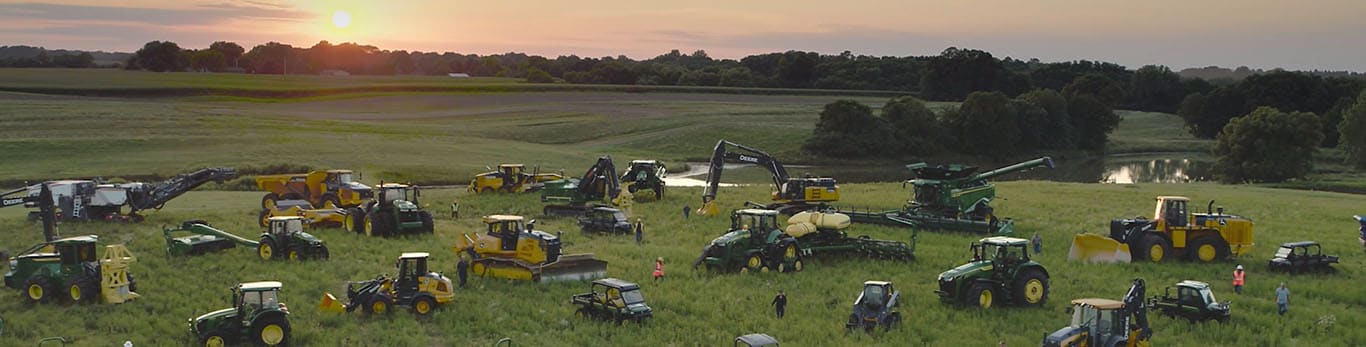 広大な畑の中で、何種類もの John Deere の機械に囲まれて歩く人たち。