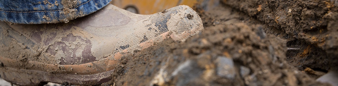 A mud covered boots steps forward