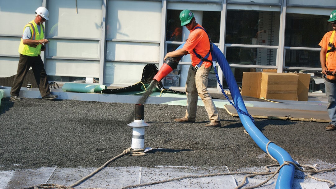 Workers use Express Blower equipment to apply materials to create a green roof.