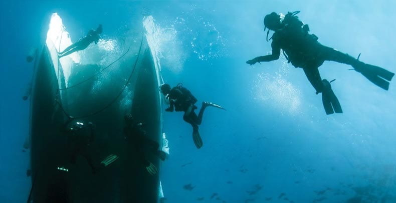 Divers under water with a ship and fish