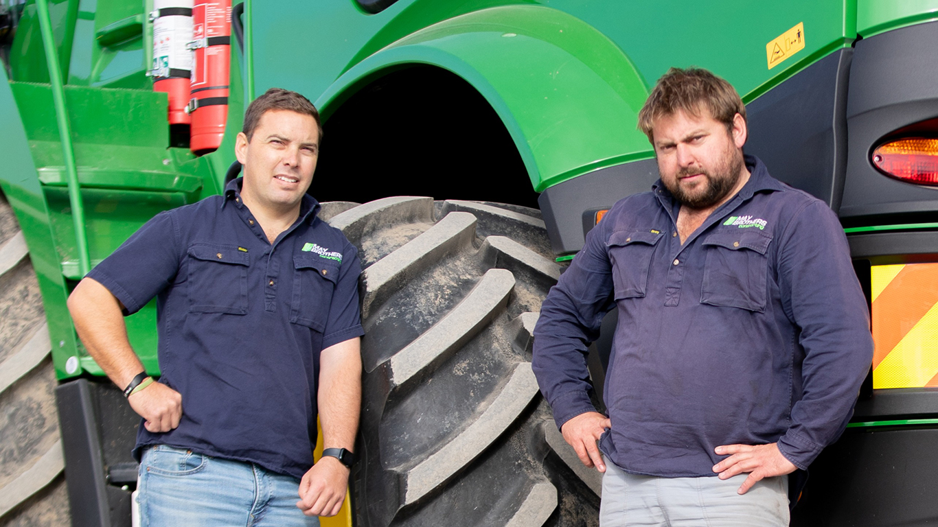 Phil and Tim May in front of a John Deere machine