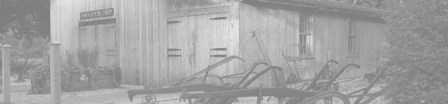 緑の背景に John Deere の元の鍛冶屋を再現した史跡の白黒写真