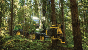 John Deere harvester removing tree trunk in forest