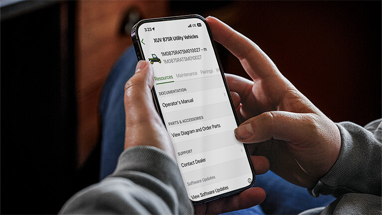 Close-up image of hands holding a cell phone looking at machine information.