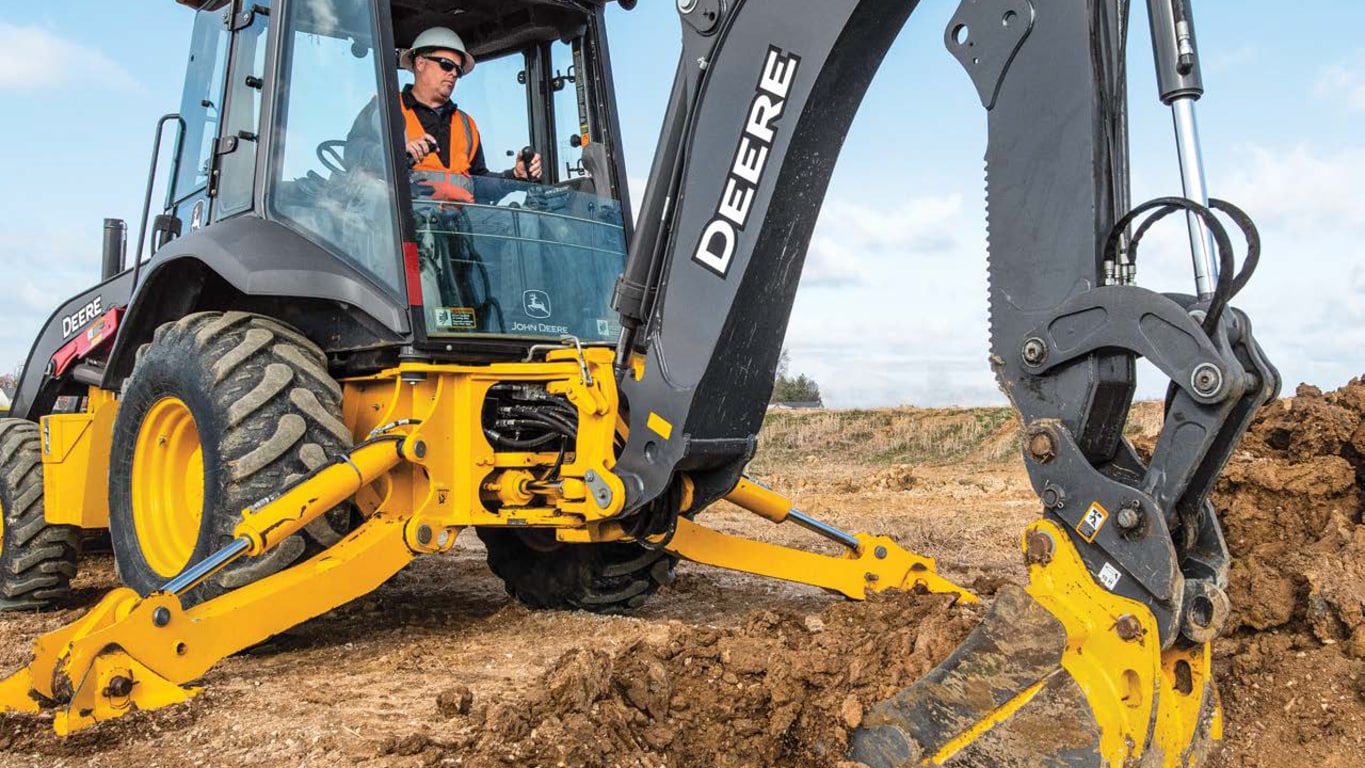 A close-up of an operator using the 310P-Tier Backhoe to scoop dirt.