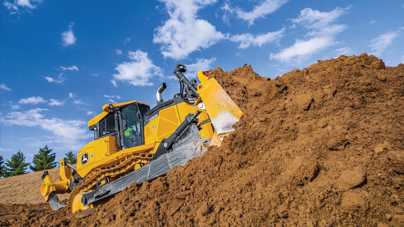 A 1050K Dozer pushing dirt on a hill at a worksite.