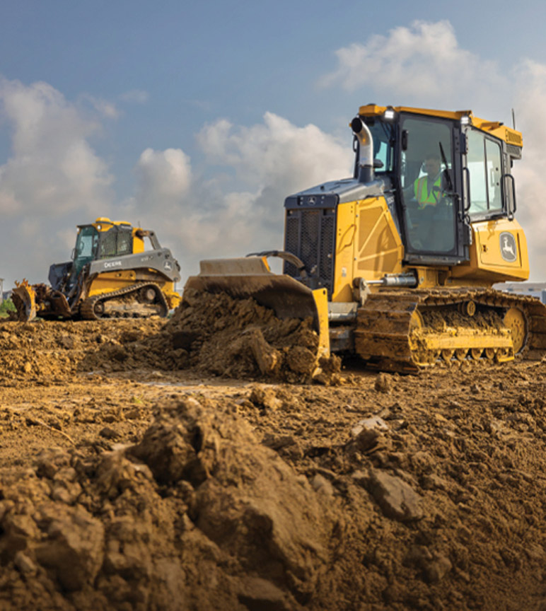 Two construction vehicles, a bulldozer and a skid steer loader, moving dirt on a construction site.