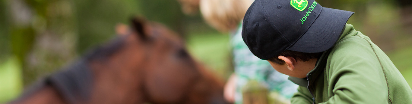 kid wearing a hat and looking at a horse