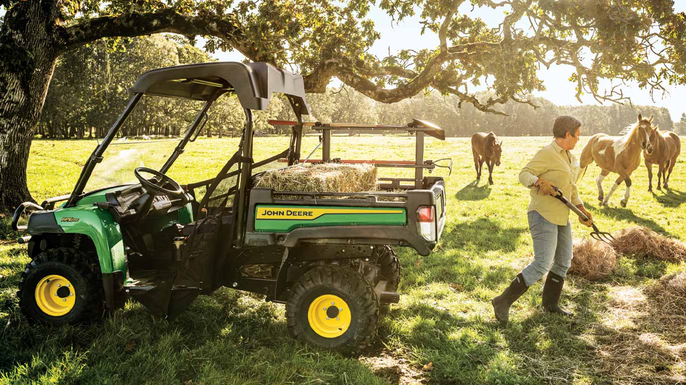 woman shoveling hay into a work series Gator™ in a field woman shoveling hay into a work series Gator™ in a field