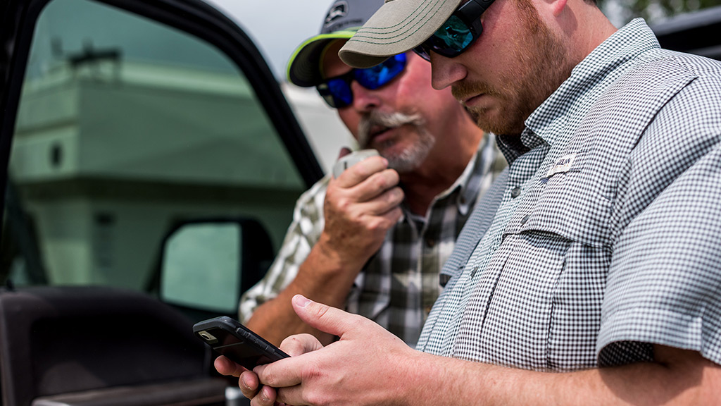 two farmers checking out John Deere Operations Center™ on a mobile phone