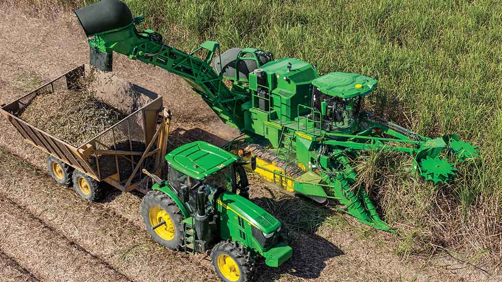 Overhead photo showing a CH Series Sugar Harvester unload crop into a tractor-pulled grain cart. Overhead photo showing a CH Series Sugar Harvester unload crop into a tractor-pulled grain cart.