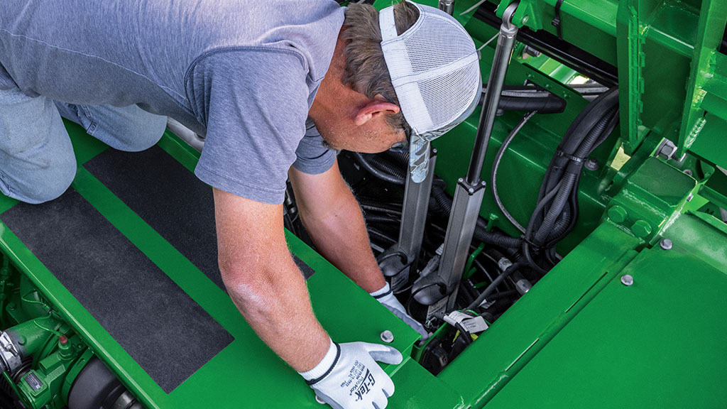 Close-up photo showing a farmer accessing the engine in a CH Series Sugar Harvester. Close-up photo showing a farmer accessing the engine in a CH Series Sugar Harvester.