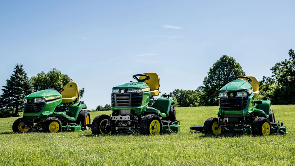 Three riding lawn tractors on a lawn in the sun.