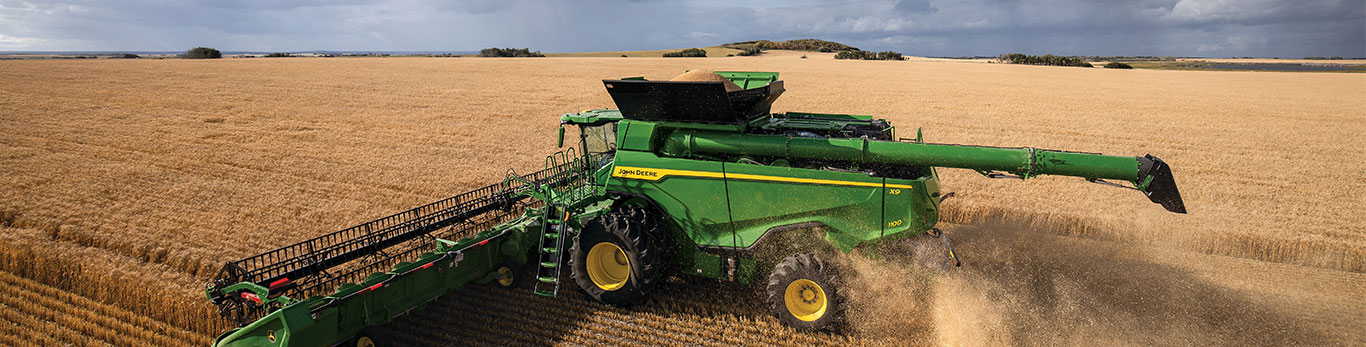 John Deere X9 Combine with header harvesting small grain wheat field
