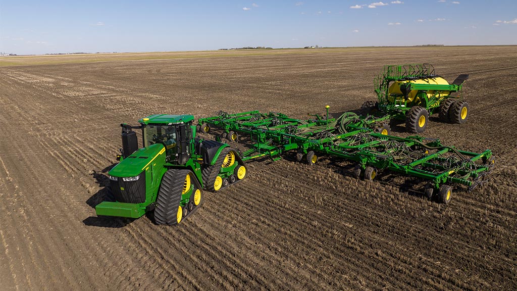 John Deere 4WD Tractor pulling small grains seeding equipment and doing an automatic end row turn in a paddock enabled by AutoTrac Turn Automation.