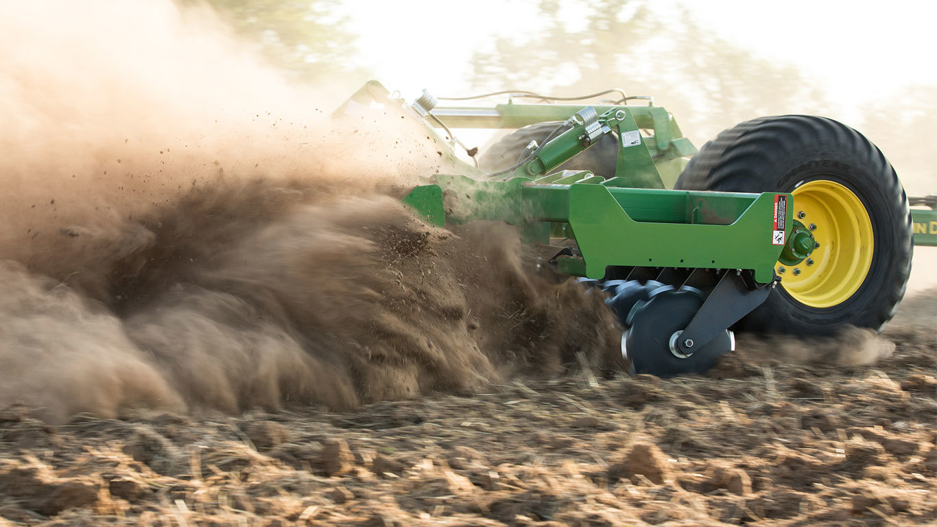 Closeup of a 2680H tillage disk creating a dust cloud in a field.