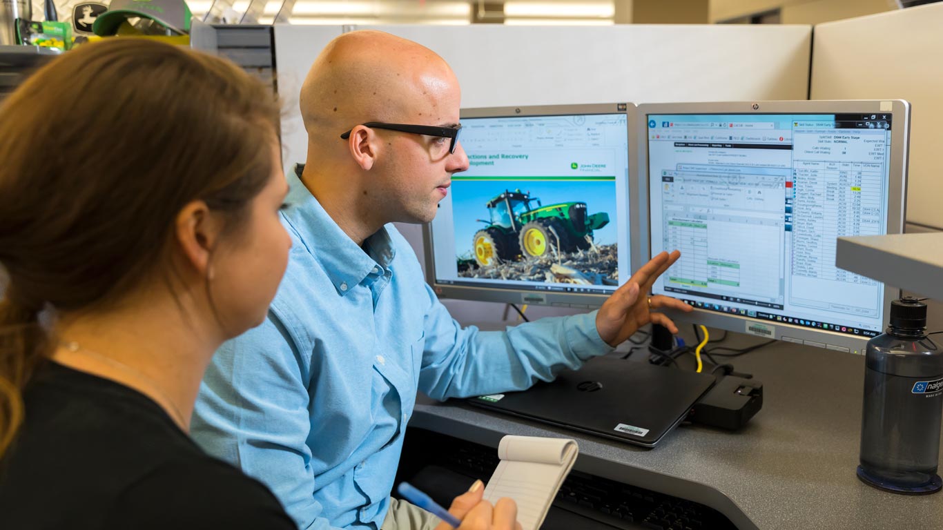 a man and a woman working in front of computer monitors a man and a woman working in front of computer monitors