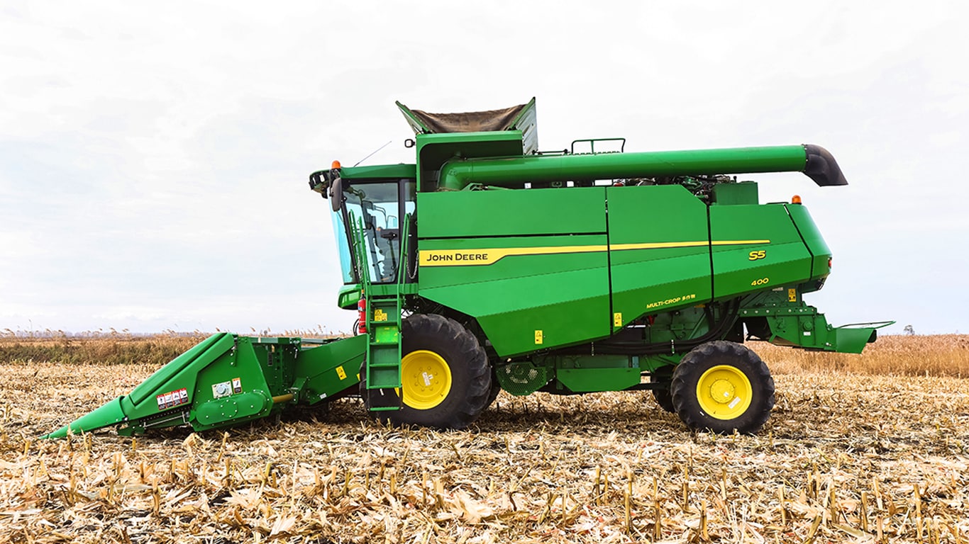 John Deere combine harvester with wide grain header on a white background