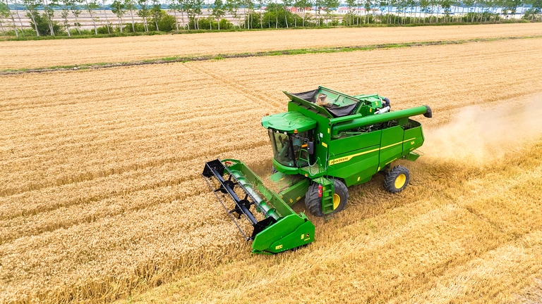 combine harvester with wide grain header on a white background, showing full machine design and front