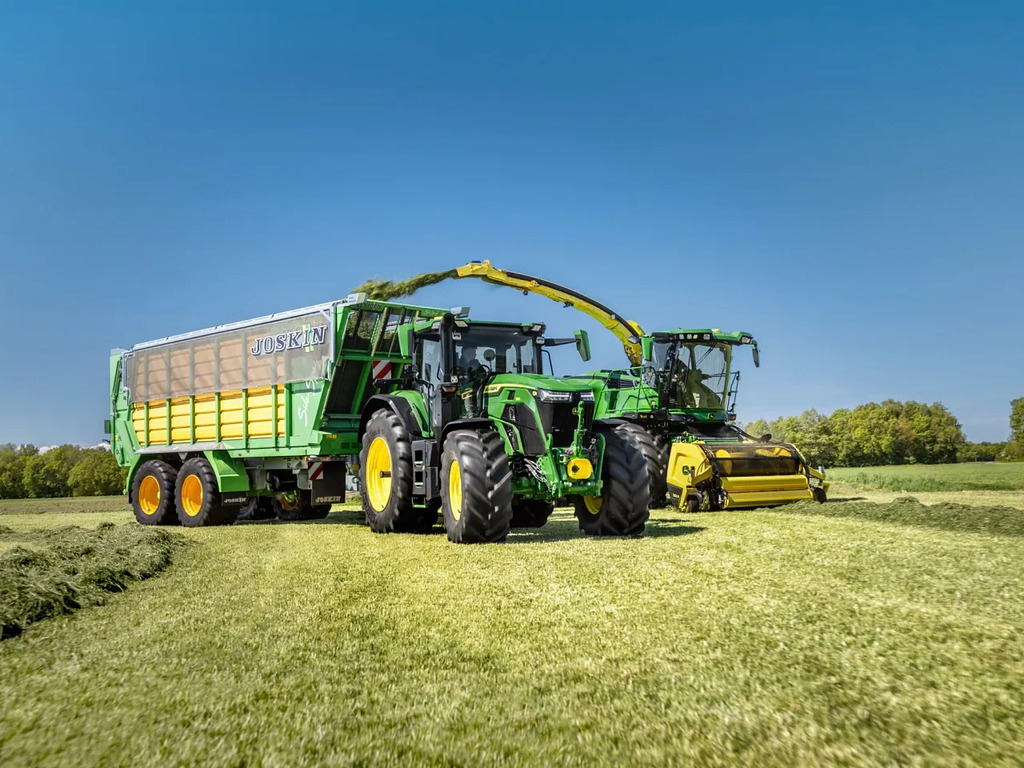 Grass silage harvesting with John Deere tractor and Joskin forage wagon in a green field