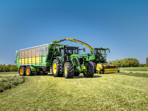 Grass silage harvesting with John Deere tractor and Joskin forage wagon in a green field