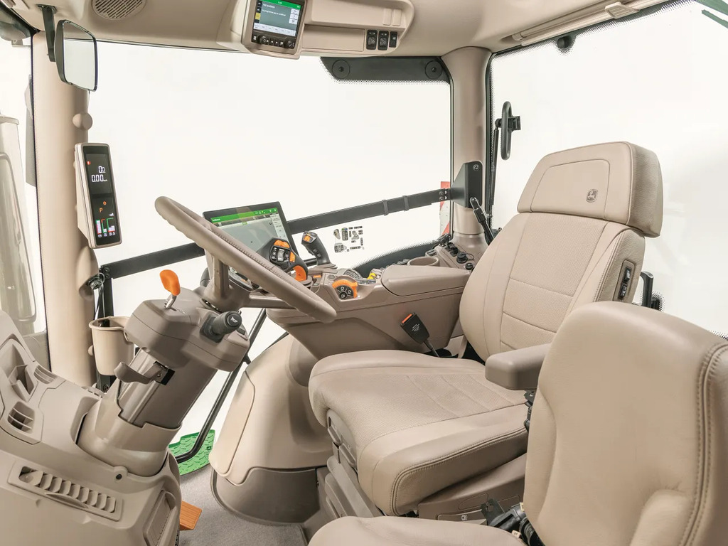 John Deere tractor cab interior with premium seat, touchscreen display and CommandARM controls in a clean studio view.